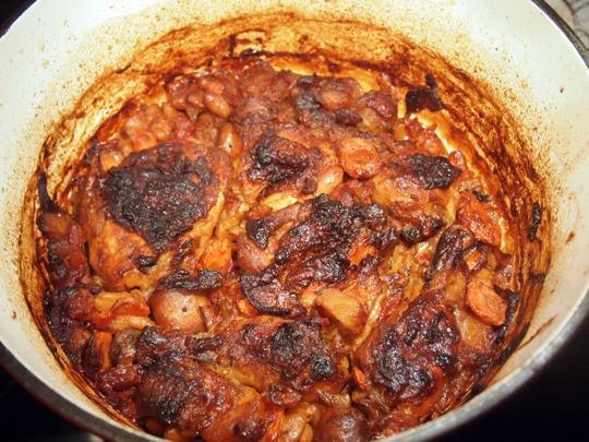 After baking in the oven, the cassoulet will start to develop a thick, dark crust.