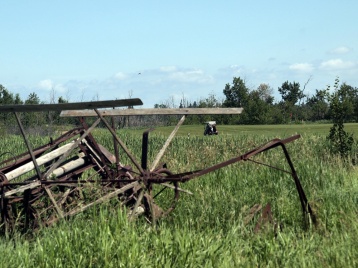 Golfers at Whitetail Crossing head down the fairway. Rusting farm equipment reminds of the region's agricultural history.